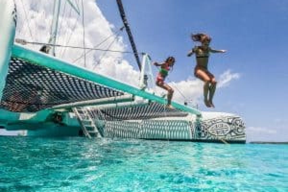 Dos personas saltan desde un velero a aguas turquesas claras bajo un cielo soleado durante el Snorktocht 3 en 1 (Curazao).