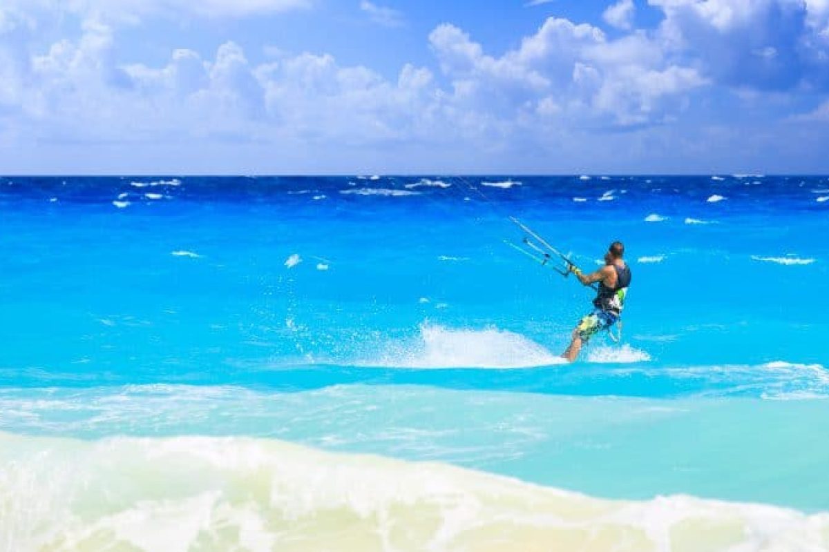 Experience the Klein Curacao Sunset Cruise (Curaçao): sail under a partially cloudy sky with shimmering blue ocean waves, splashes of water and white foam in the foreground while enjoying unforgettable sunset.