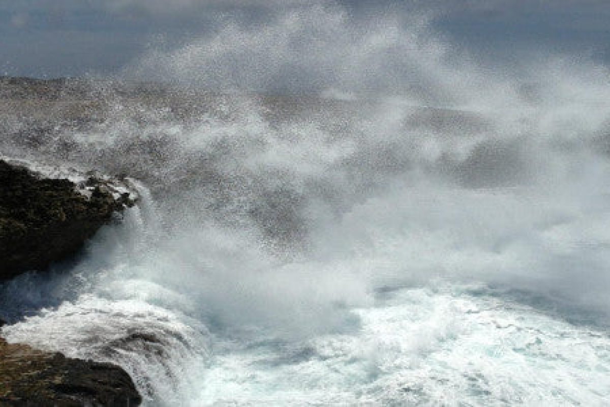 Ervaar de energie van de Curaçaose kust tijdens een Snorkel en strandavontuur: krachtige oceaangolven beuken tegen ruige kliffen onder een bewolkte hemel, waarbij witte nevel en kolkend water een dramatisch, onvergetelijk tafereel creëren.